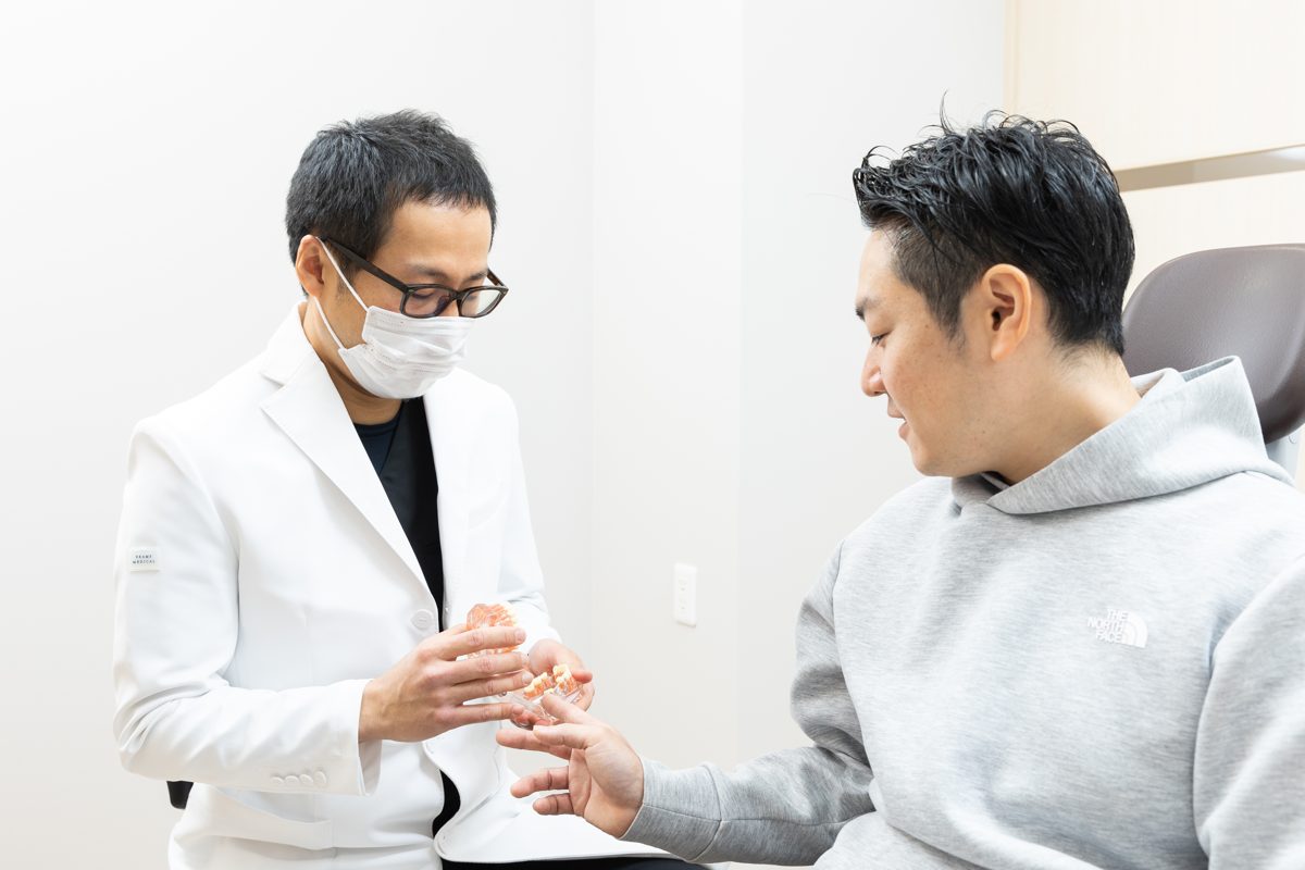 院長が歯列模型を手に患者さんへ説明する様子